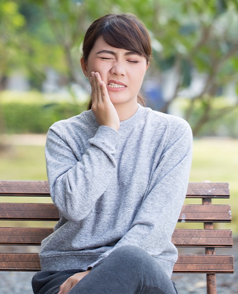 Woman in need of emergency dentistry holding jaw in pain